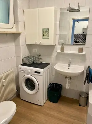 a bathroom with a washing machine and a sink at Garden Pool Apartment in Merano