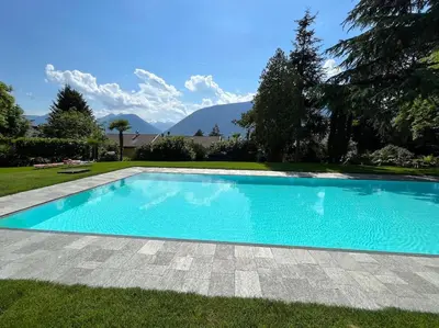 a swimming pool in a yard with mountains in the background at Garden Pool Apartment in Merano