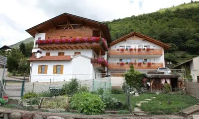 a large white house with flowers in front of it at Ferienwohnungen Kaltenbachhof - Urlaub auf dem Biobauernhof in Parcines