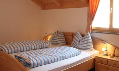 a bed with blue and white pillows and a window at Ferienwohnungen Kaltenbachhof - Urlaub auf dem Biobauernhof in Parcines