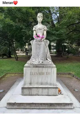 a statue of a woman holding flowers in a park at Appartamento Merano nel cuore in Merano