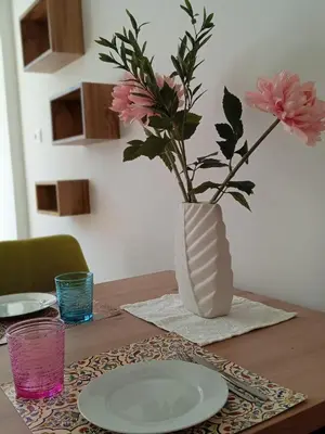 a vase with flowers sitting on a table with plates at Apartment Himmelreich 29 in Plaus