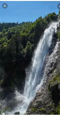 a waterfall on the side of a mountain with trees at Apartment Himmelreich 29 in Plaus
