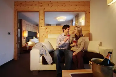 a man and woman sitting on a couch in a room at Romantik Villa Cesanueva in Selva di Val Gardena