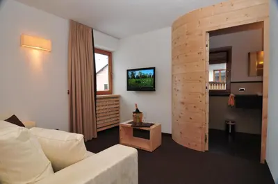 a living room with a white couch and a tv at Romantik Villa Cesanueva in Selva di Val Gardena