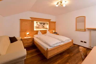 a bedroom with a large bed and a couch at Romantik Villa Cesanueva in Selva di Val Gardena