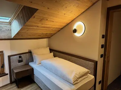 a bed in a room with a wooden ceiling at Romantik Villa Cesanueva in Selva di Val Gardena