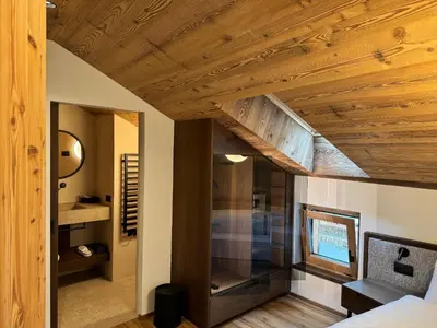 a bedroom with a wooden ceiling and a mirror at Romantik Villa Cesanueva in Selva di Val Gardena