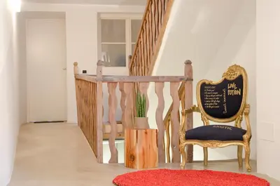 a staircase with a chair and a red rug at Stay COOPER l Goethe Guesthouse in Bolzano