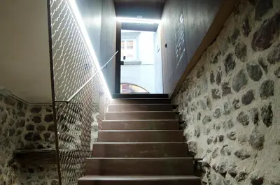 a staircase in a house with a stone wall at Stay COOPER l Goethe Guesthouse in Bolzano