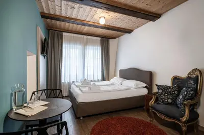 a bedroom with a bed and a table and a chair at Stay COOPER l Goethe Guesthouse in Bolzano