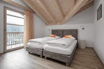 two beds in a bedroom with a large window at Ciasa de Lenz in San Cassiano