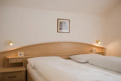 a bedroom with a white bed with a wooden headboard at Pension Siller in Lagundo