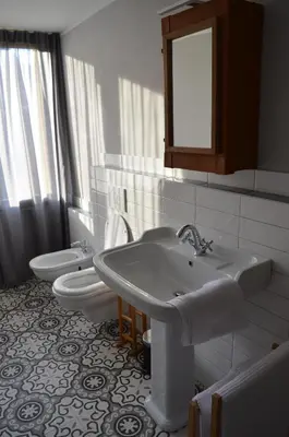 a bathroom with two sinks and a toilet and a mirror at Villa Iolanda in Merano