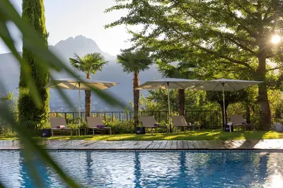 a swimming pool with umbrellas and chairs next to it at Parkhotel Marlena - Adults Only in Merano