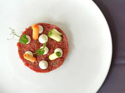 a white plate with a meat dish with vegetables on it at Parkhotel Marlena - Adults Only in Merano