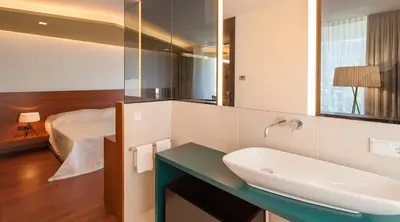a bathroom with a sink and a bed at Parkhotel Marlena - Adults Only in Merano