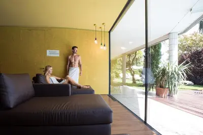 a man and a woman sitting on a couch in a living room at Parkhotel Marlena - Adults Only in Merano