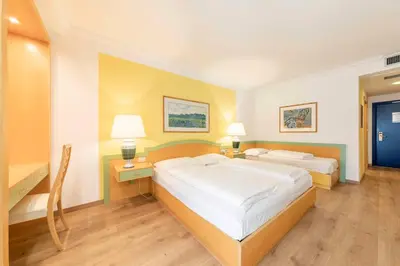 a bedroom with two beds and a desk and two lamps at Business Resort Parkhotel Werth in Bolzano