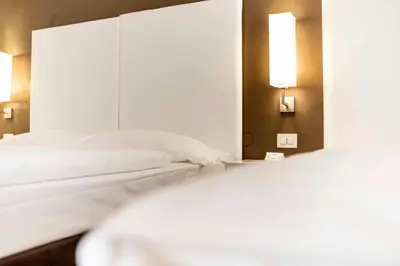 two white beds in a room with a mirror at Business Resort Parkhotel Werth in Bolzano