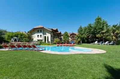 a pool in a yard with chairs and a house at Business Resort Parkhotel Werth in Bolzano