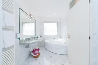 a white bathroom with a tub and a sink at Business Resort Parkhotel Werth in Bolzano