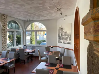 a dining room with tables and chairs and windows at Albergo Cavallino s'Rössl in Merano