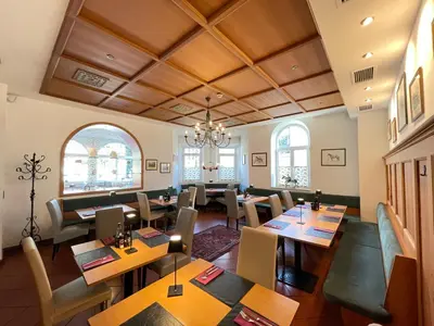 a restaurant with wooden ceilings and tables and chairs at Albergo Cavallino s'Rössl in Merano