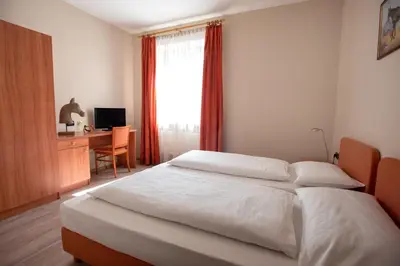 a bedroom with a bed and a desk and a window at Albergo Cavallino s'Rössl in Merano