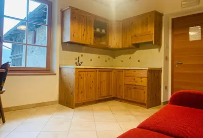 a kitchen with wooden cabinets and a red couch at Agritur Maso Forcola in Brez