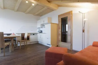 a living room with a couch and a table and a kitchen at Wargerhof - Urlaub auf dem Bauernhof in Meltina