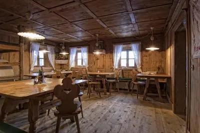 a dining room with wooden floors and tables and windows at Wargerhof - Urlaub auf dem Bauernhof in Meltina