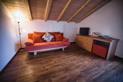 a living room with an orange couch and a television at Wargerhof - Urlaub auf dem Bauernhof in Meltina
