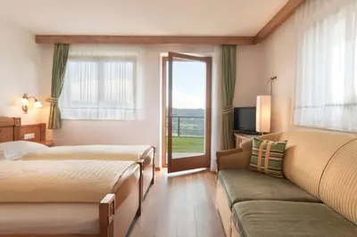 a bedroom with two beds and a couch and a window at Wargerhof - Urlaub auf dem Bauernhof in Meltina