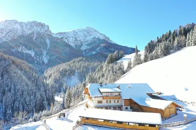 a large white building on a road next to a mountain at ALMRESIDENZ UNTERRAIN - with FREE SKI BUS SHUTTLE in Valdaora