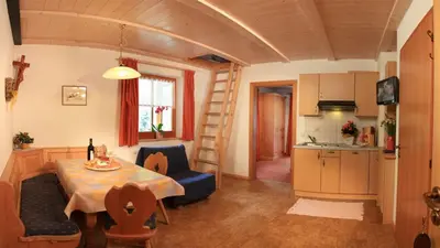 a living room with a table and a kitchen with a ladder at Residence Landhaus Rainer in Ridanna