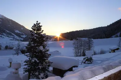 a snow covered yard with a christmas tree and the sunset at Residence Landhaus Rainer in Ridanna