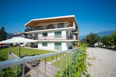 a white building with a balcony and an umbrella at Apartment Edelweiss in Brunico
