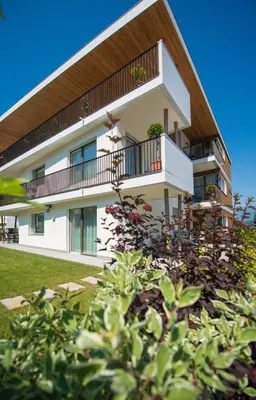 a white building with a balcony and some bushes at Apartment Edelweiss in Brunico