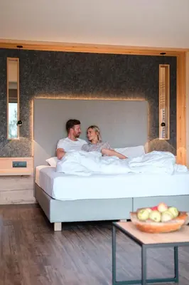 a man and a woman sitting on a bed at Hotel Salten in Avelengo