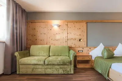 a hotel room with a couch and a bed at Hotel Salten in Avelengo