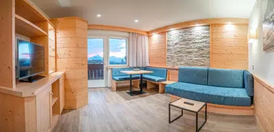a living room with a blue couch and a television at Hotel Salten in Avelengo