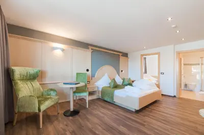 a bedroom with a bed and a table and a chair at Hotel Salten in Avelengo