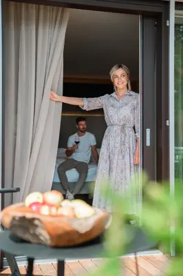 a woman in a dress standing next to a curtain at Hotel Salten in Avelengo