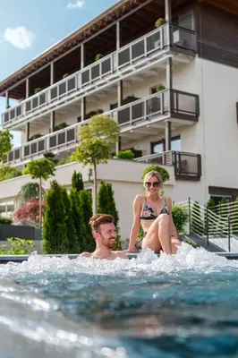 a man and a woman sitting in the water at Hotel Salten in Avelengo