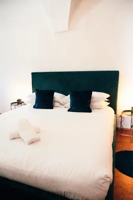 a bed with white sheets and blue pillows at Franz Haus Apartments in Merano