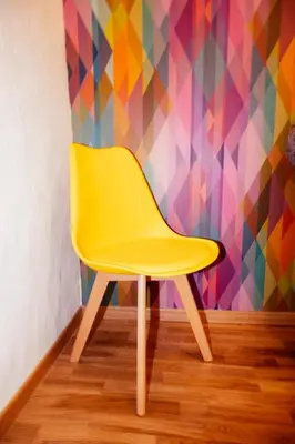 a yellow chair in front of a colorful wall at Franz Haus Apartments in Merano
