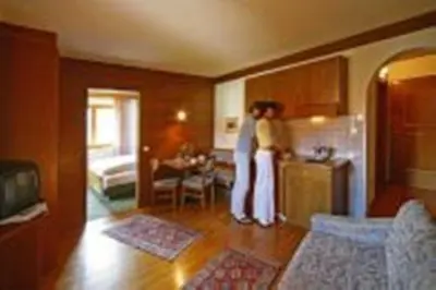 two women standing in a kitchen with a refrigerator at Hotel Garní Sunnleit´n in Monguelfo