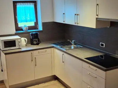 a kitchen with white cabinets and a sink and a window at Villa Sella in Selva di Val Gardena