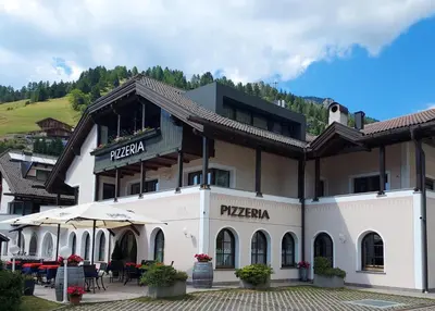a hotel in the mountains with tables and chairs at Villa Sella in Selva di Val Gardena